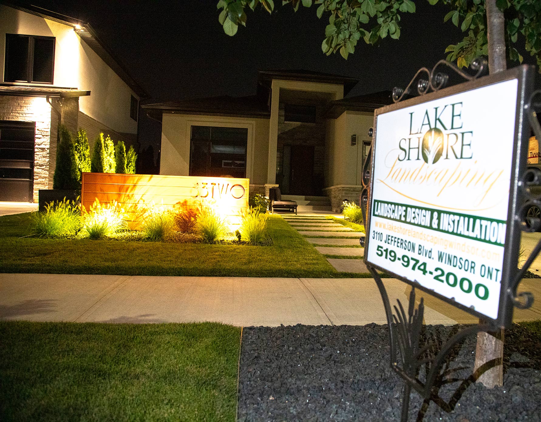 Outdoor lighting work with "lakeshore landscaping" sign in foreground.